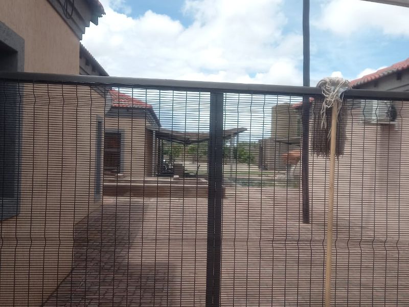 A view of the rear courtyard and paved area secured by a metal gate, showing the exterior facade of the property.