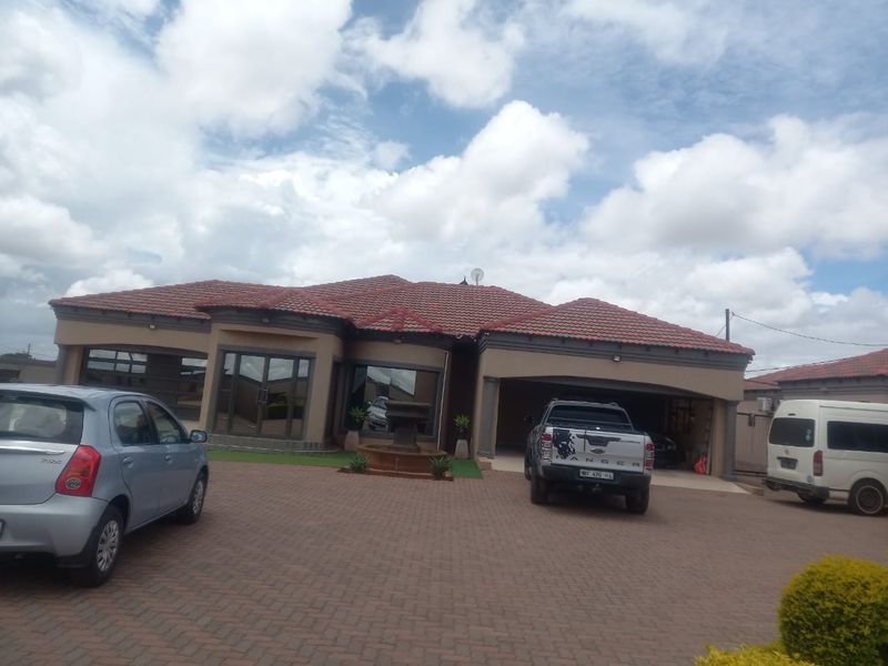 Front elevation of a well-maintained house featuring a tiled roof, paved driveway, and an integrated garage with a central stone fountain feature.