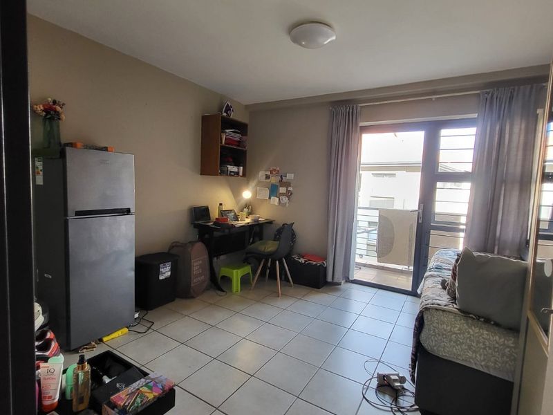 A bedroom featuring tiled flooring and a sliding glass door providing access to a balcony, with neutral wall finishes.