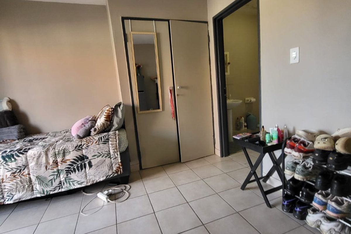 A bedroom featuring tiled flooring and a built-in cupboard, with direct access to an en-suite bathroom.