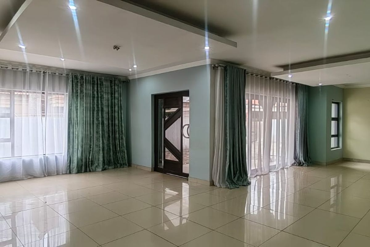 Spacious, light-filled living area featuring modern recessed ceilings, downlights, and large windows with tiled flooring throughout.