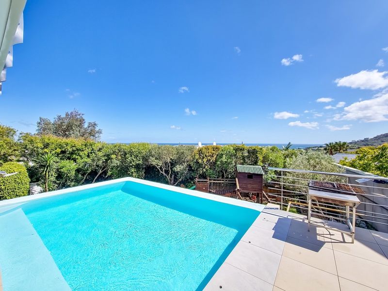 Elevated pool area featuring a modern swimming pool, tiled deck, and stainless steel balustrade with scenic views.