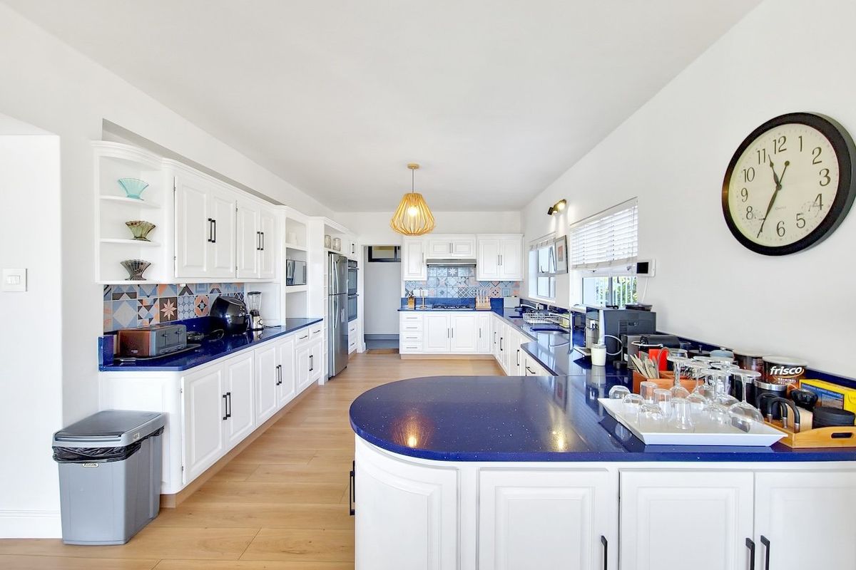 Spacious kitchen featuring white cabinetry, vibrant blue stone countertops, patterned tile backsplash, and light wood-look flooring with ample counter space.