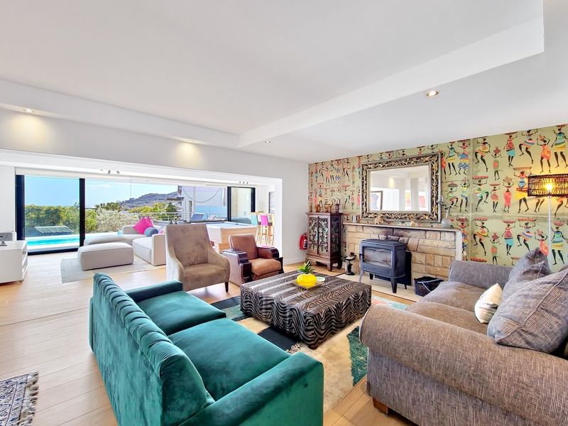Spacious open-plan living area featuring a stone fireplace with a wood-burning stove, timber flooring, and large sliding doors opening to an outdoor patio.