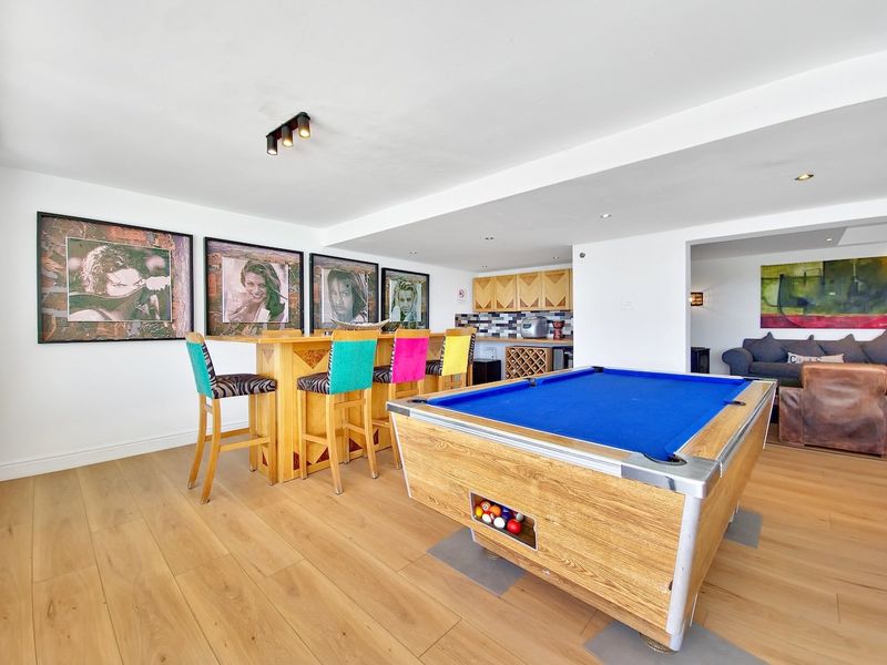 A well-appointed entertainment area featuring a built-in bar with integrated wine storage, recessed lighting, and durable laminate flooring.