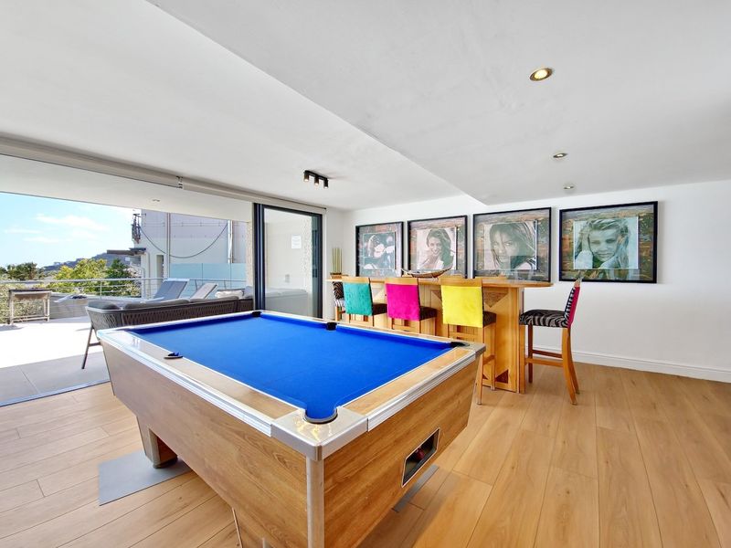 Spacious living area featuring wood-look tile flooring, recessed lighting, and large sliding glass doors opening onto an outdoor patio space.