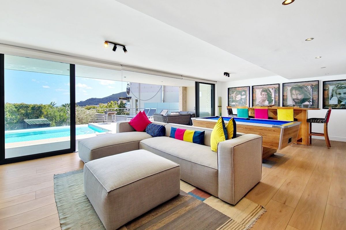 Spacious living area featuring hardwood floors, recessed lighting, and large sliding glass doors opening to a pool deck with scenic views.