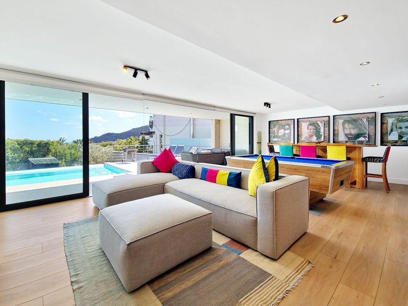 Spacious living area featuring hardwood floors, recessed lighting, and large sliding glass doors opening to a pool deck with scenic views.