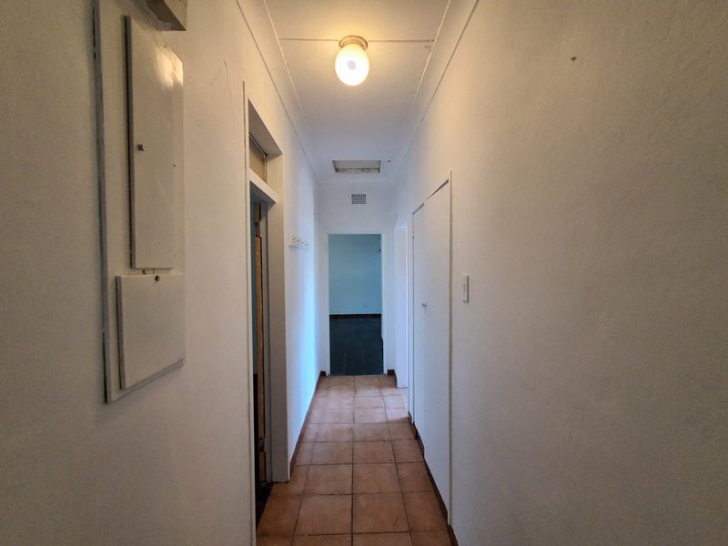 A functional hallway featuring tiled flooring, built-in storage cupboards, and an electrical distribution board, providing access to other areas of the home.