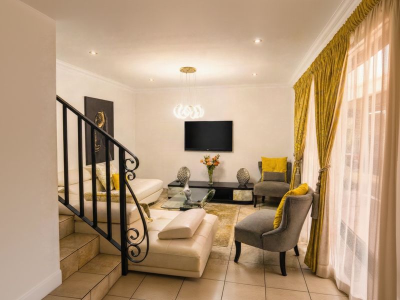 A well-lit living room featuring tiled flooring, a decorative wrought iron staircase railing, and large sliding glass doors leading to the exterior.