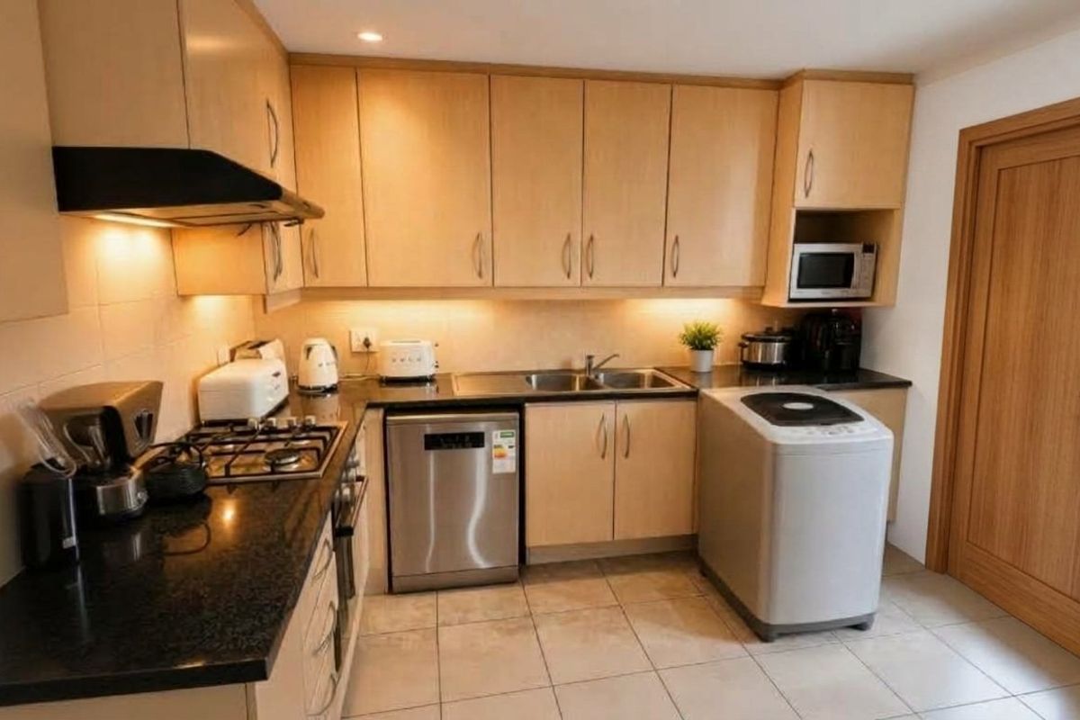 A functional kitchen featuring light wood cabinetry, granite countertops, a gas hob, extractor fan, and integrated microwave with tiled flooring.