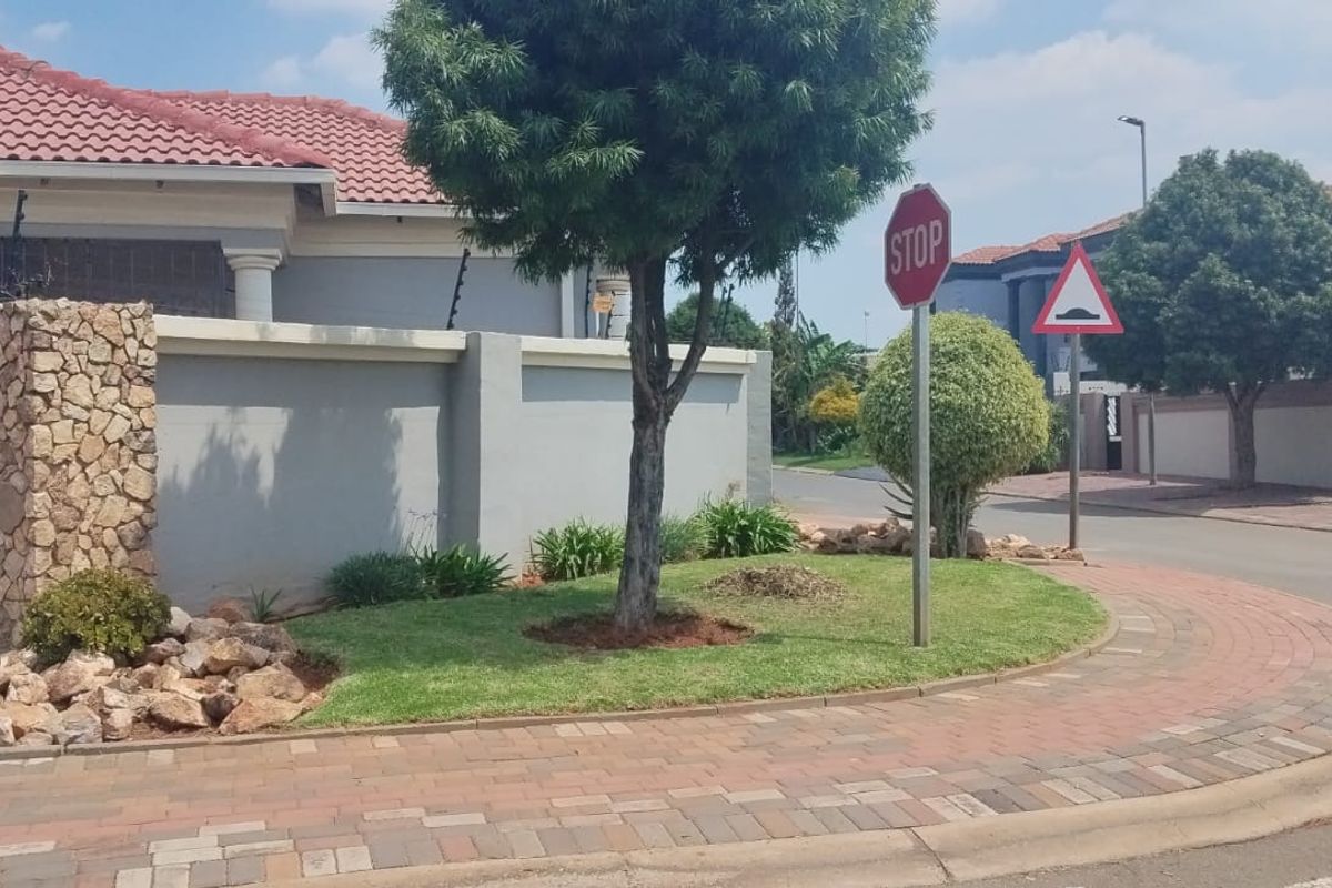 Street view of the property showing the front boundary wall, stone feature pillar, electric fencing, and paved driveway area.