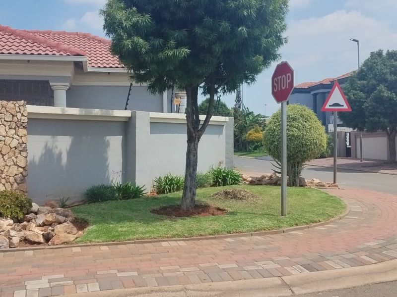 Street view of the property showing the front boundary wall, stone feature pillar, electric fencing, and paved driveway area.