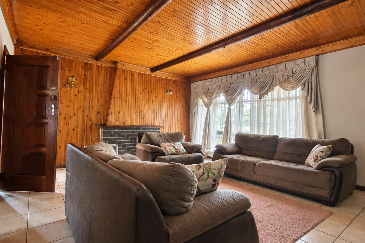 A living room featuring extensive timber-clad walls and ceiling, a brick fireplace, and tiled flooring, offering a traditional aesthetic with potential for modernization.