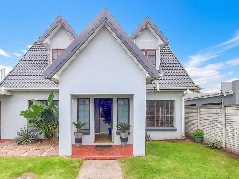 Front elevation of a double-story residential home featuring a gabled roof design, tiled entrance porch, and a well-maintained front garden with boundary walling.