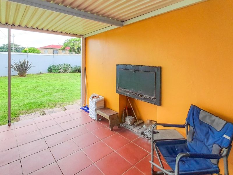 Covered patio area featuring a built-in braai, tiled flooring, and direct access to the rear garden.