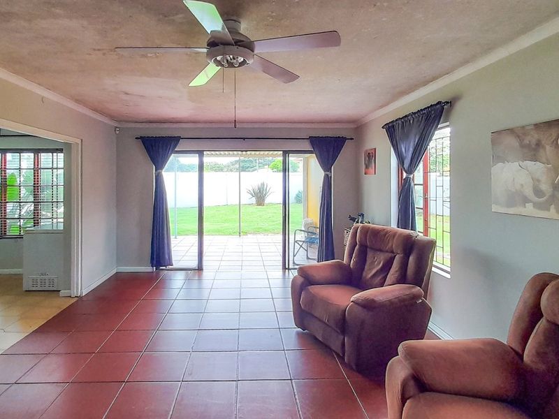 Spacious living room featuring tiled flooring, a ceiling fan, and large sliding glass doors providing direct access to the rear garden.