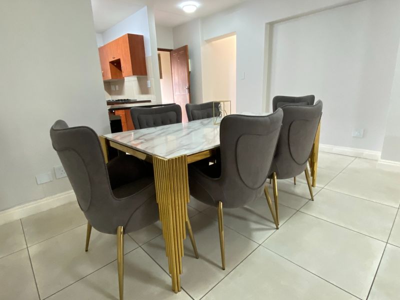Open plan dining area featuring tiled flooring, flowing into a functional kitchen space with built-in cabinetry and stove.