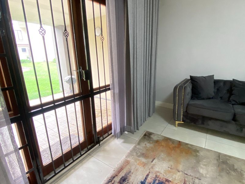 A living room area featuring tiled flooring and a secure sliding door leading to an outdoor patio space.