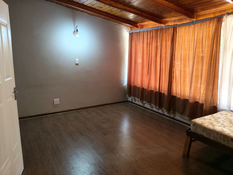A spacious bedroom featuring exposed timber beam ceilings and laminate flooring, offering a neutral canvas ready for personalization.