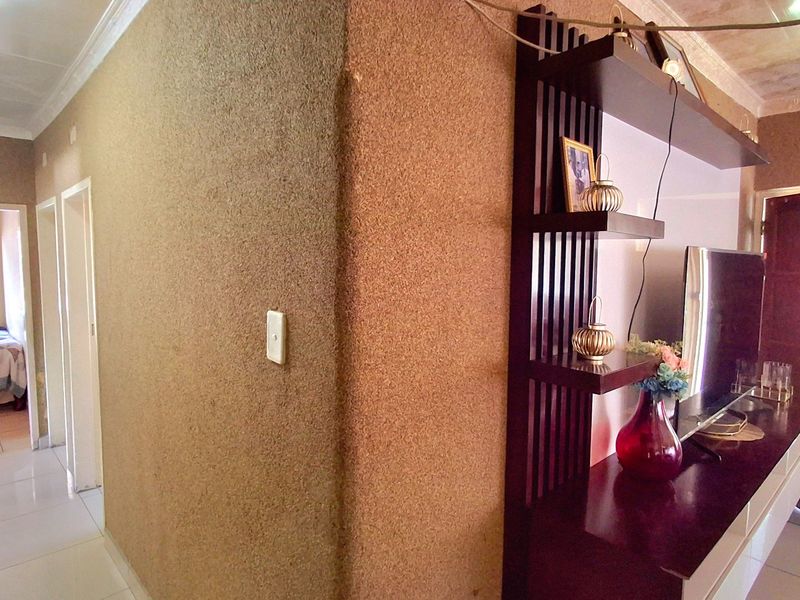 Living area featuring tiled flooring and a built-in shelving unit, with a view into an adjacent bedroom.