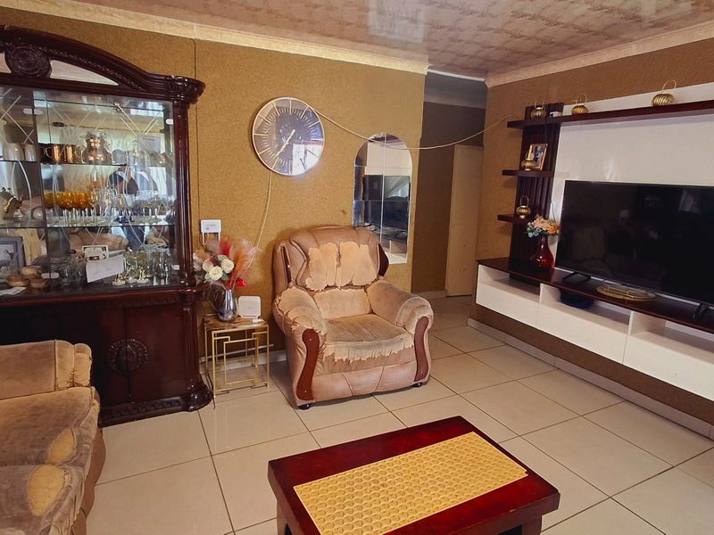 A living room featuring tiled flooring, textured wall finishes, and a built-in media console unit.