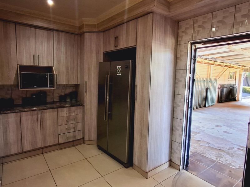 A functional kitchen featuring wood-grain cabinetry, granite countertops, built-in microwave, and tiled flooring, with direct access to an outdoor area.