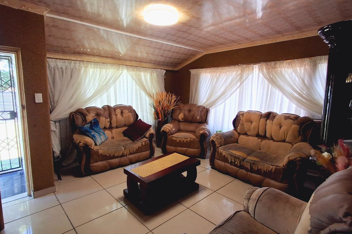 A living room featuring tiled flooring and ceiling panels, with direct access to an exterior entrance via a security gate.