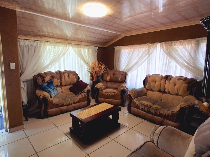 A living room featuring tiled flooring and ceiling panels, with direct access to an exterior entrance via a security gate.