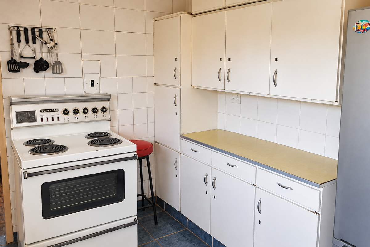 A functional kitchen featuring white built-in cabinetry, laminate countertops, tiled backsplash, and a classic freestanding electric stove.