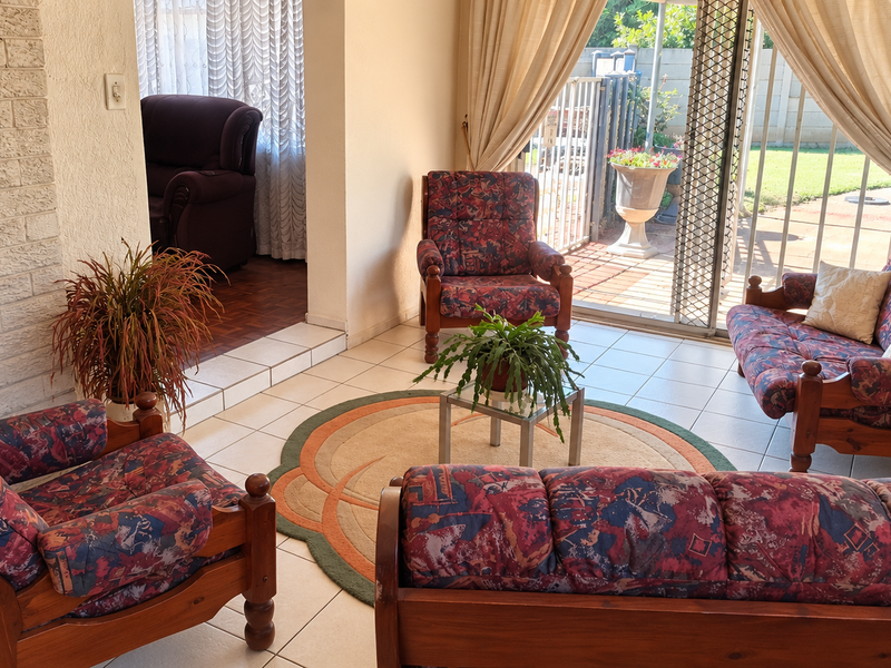 A living room featuring a brick fireplace, tiled flooring, and a sliding glass door providing access to the outdoor patio area.