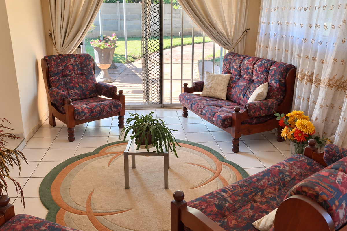 A bright living room featuring tiled flooring and a sliding glass door providing direct access to the rear patio and garden area.