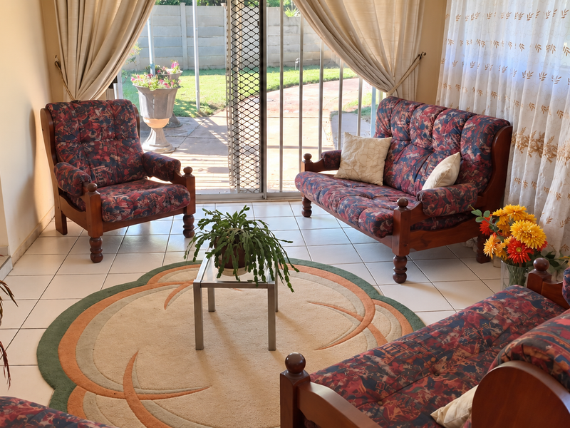 A bright living room featuring tiled flooring and a sliding glass door providing direct access to the rear patio and garden area.