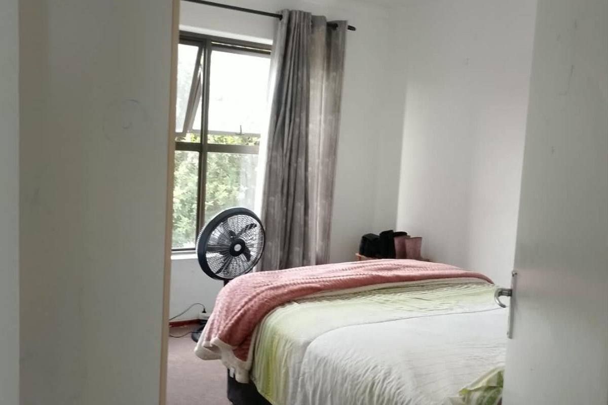 A compact bedroom featuring carpeted flooring and a window with curtain rails, requiring minor cosmetic updates to refresh the space.
