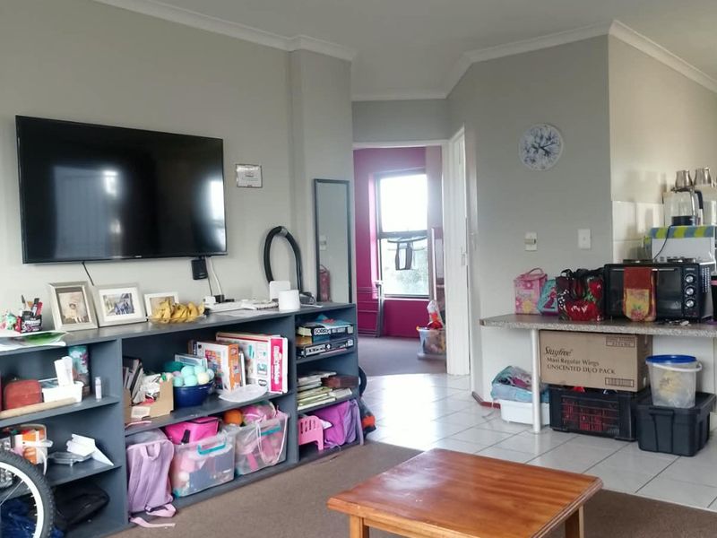Open plan living area featuring a combination of tiled and carpeted flooring, with a kitchen counter and neutral wall finishes.