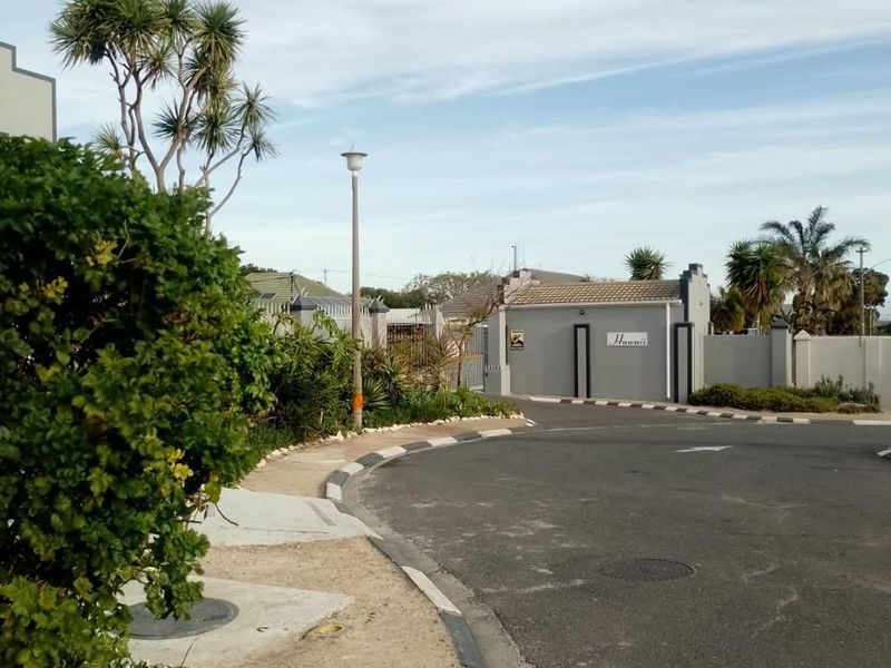 A view of the street approach and entrance to the Hawaii apartment complex, featuring paved roads and perimeter boundary walls.