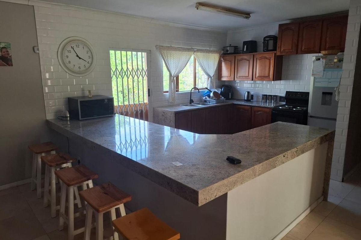Functional kitchen featuring granite countertops, a breakfast bar, subway tile backsplash, and traditional wooden cabinetry with direct access to the exterior.