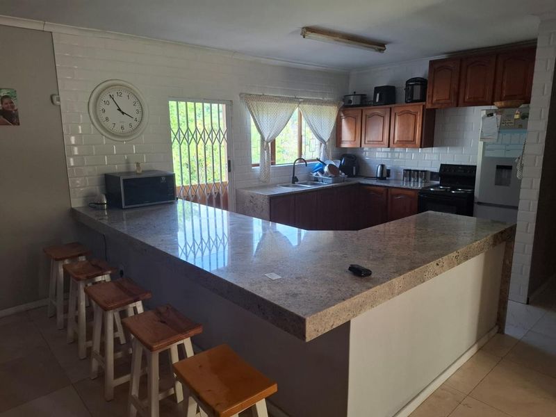 Functional kitchen featuring granite countertops, a breakfast bar, subway tile backsplash, and traditional wooden cabinetry with direct access to the exterior.