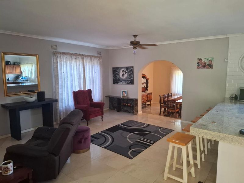 Spacious open-plan living and dining area featuring tiled flooring, a granite breakfast bar, and a classic archway connecting the two living spaces.
