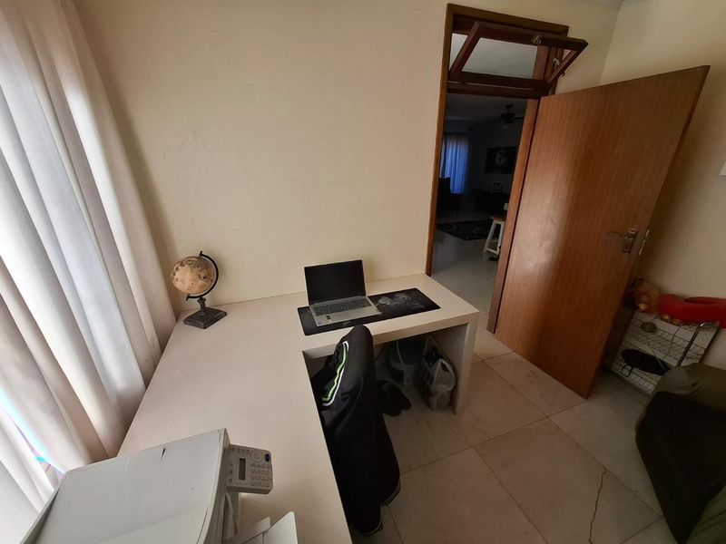 A functional home office space featuring tiled flooring and a wooden door with a transom window, providing a quiet workspace.