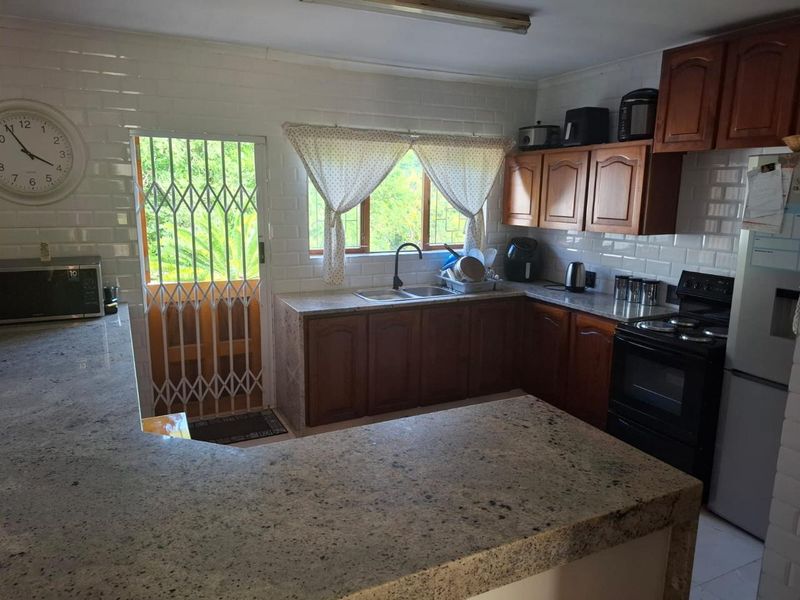 Functional kitchen featuring granite countertops, subway tile backsplash, wooden cabinetry, and direct access to the exterior via a security gate.