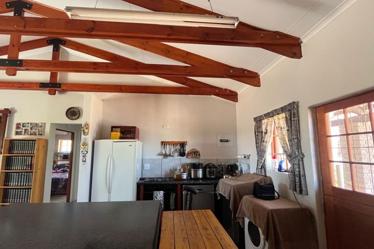 Kitchen area featuring exposed timber roof trusses, tiled backsplash, and direct access to the exterior via a glass-paned timber door.