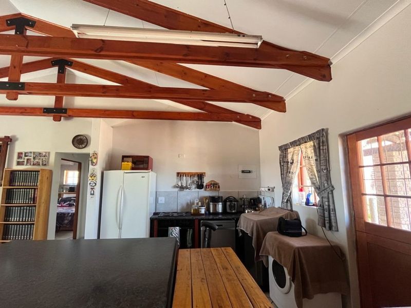 Kitchen area featuring exposed timber roof trusses, tiled backsplash, and direct access to the exterior via a glass-paned timber door.