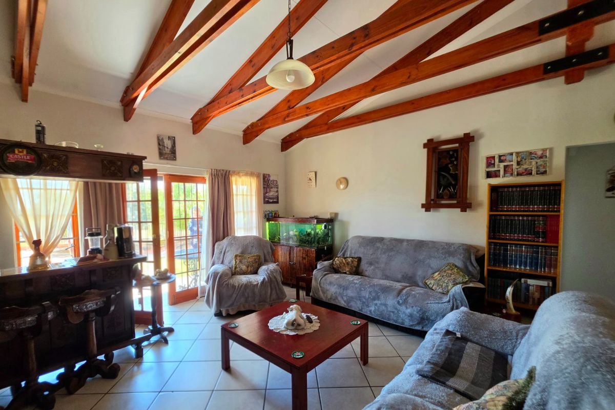 Spacious living room featuring exposed timber ceiling beams, tiled flooring, and direct access to the outdoor area through glass french doors.