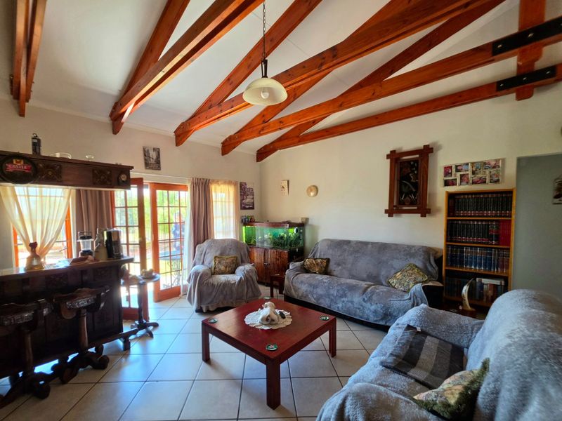 Spacious living room featuring exposed timber ceiling beams, tiled flooring, and direct access to the outdoor area through glass french doors.