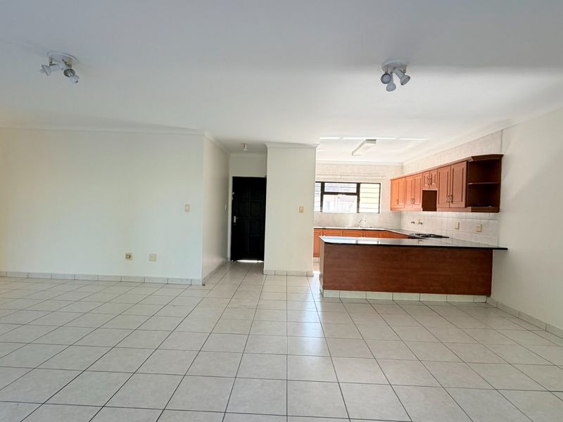 Spacious open-plan living area featuring tiled flooring and a functional kitchen with built-in cabinetry and granite countertops.
