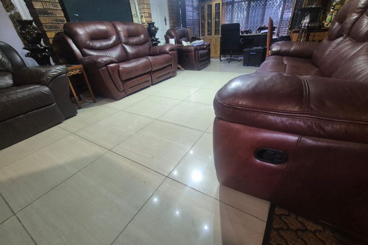 Spacious living room featuring large format floor tiles and an exposed brick feature wall, providing a solid foundation for modern interior updates.