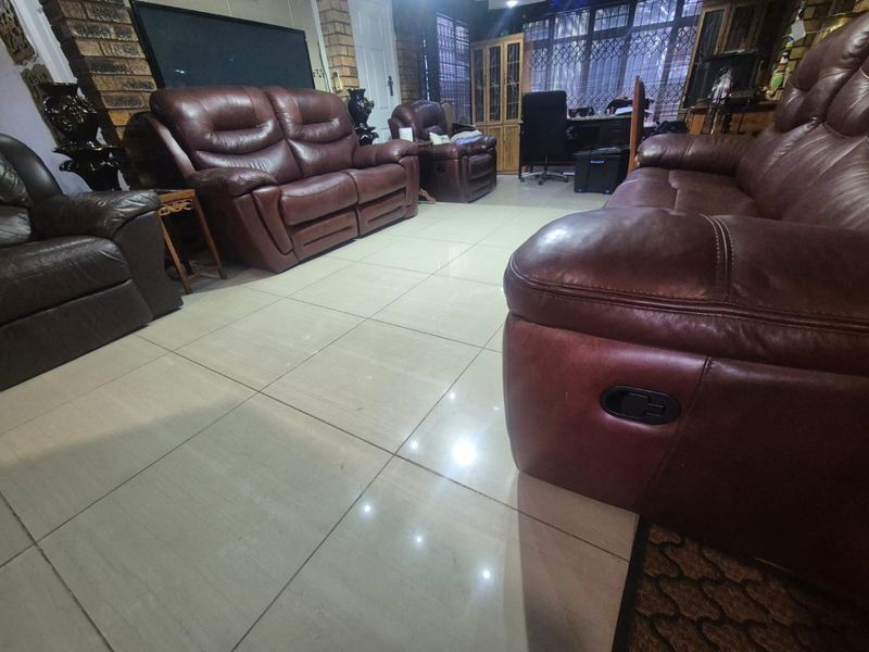 Spacious living room featuring large format floor tiles and an exposed brick feature wall, providing a solid foundation for modern interior updates.