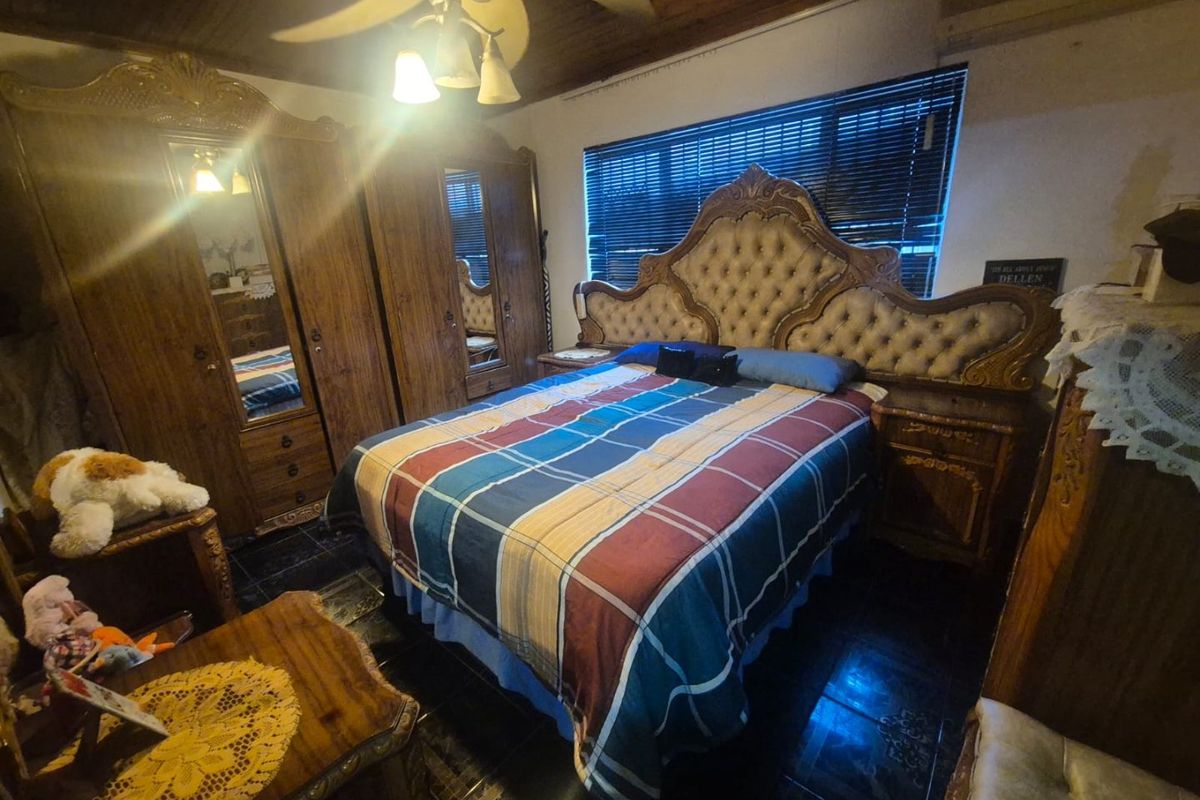 A bedroom featuring a timber ceiling, ceiling fan, and tiled flooring, providing a functional space with traditional finishes.