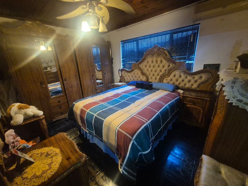 A bedroom featuring a timber ceiling, ceiling fan, and tiled flooring, providing a functional space with traditional finishes.